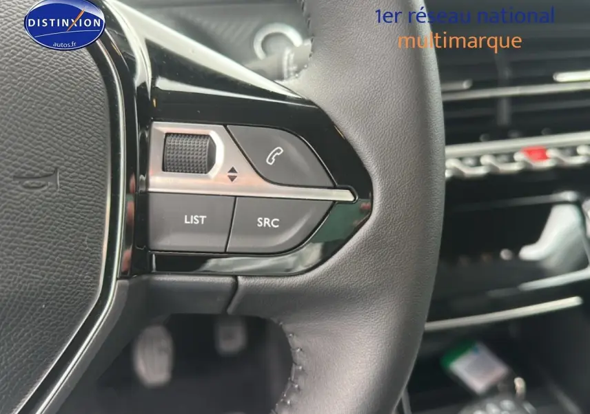 Gros plan sur les commandes au volant en cuir noir de la Peugeot 208 1.2 PureTech 100 Allure 2024.
