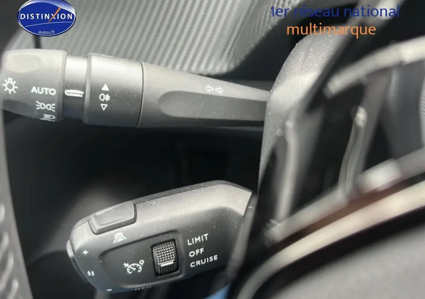 Gros plan sur les commandes du régulateur de vitesse et des phares dans l’habitacle d’une Peugeot 208 gris artense.