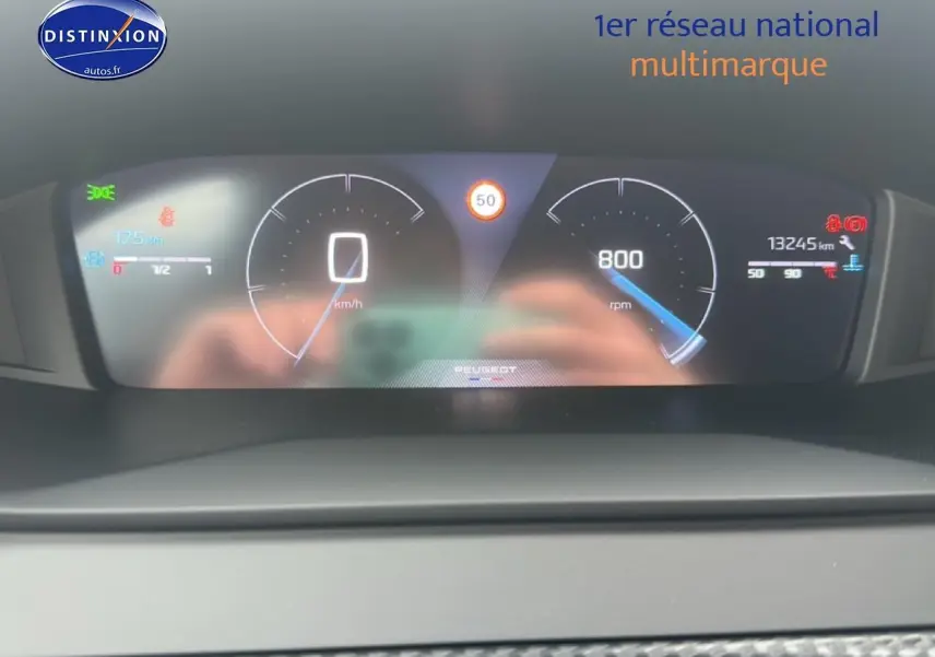Tableau de bord numérique de Peugeot 208 2024 affichant vitesse, compte-tours et alertes, vue frontale rapprochée.
