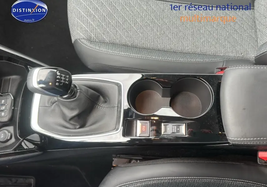 Vue plongeante sur la console centrale noire avec levier de vitesse manuel et accoudoir gris du Peugeot 208 gris Artense.