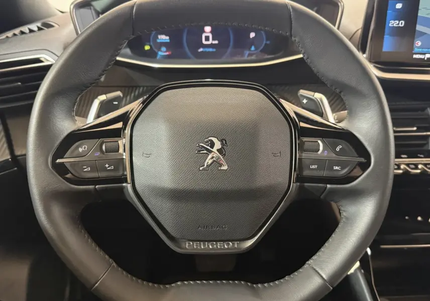 Vue rapprochée du volant cuir noir du Peugeot 2008 2023 avec commandes multifonctions et tableau de bord digital.