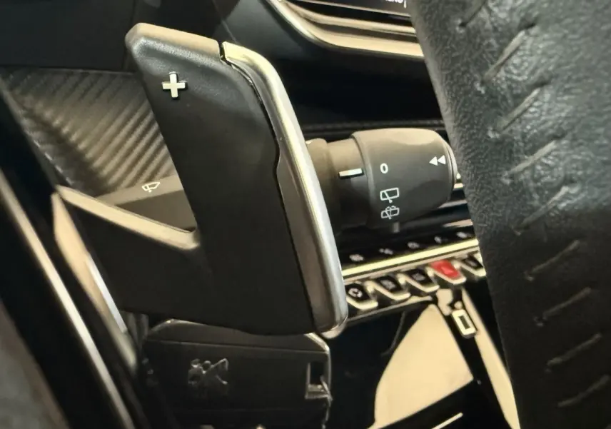 Gros plan sur la palette de changement de vitesse droite en plastique noir et chrome dans l’habitacle du Peugeot 2008 gris clair.