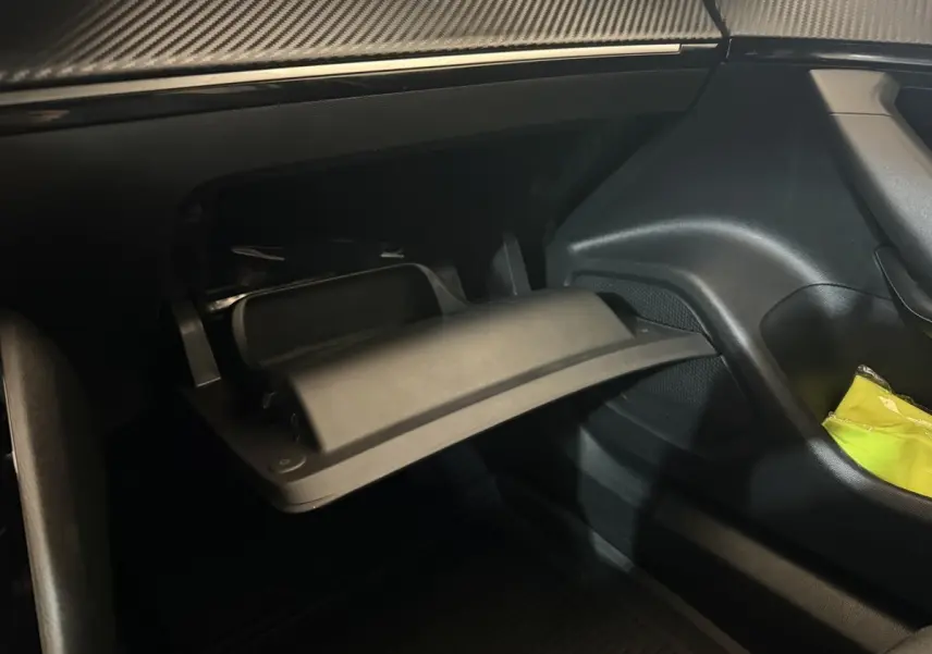 Vue intérieure côté passager du Peugeot 2008 gris clair 2023, montrant la boîte à gants ouverte et un rangement latéral.