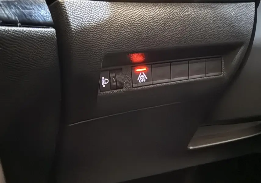 Gros plan sur les commandes noires du tableau de bord côté conducteur du Peugeot 2008 gris clair, voyant rouge allumé.