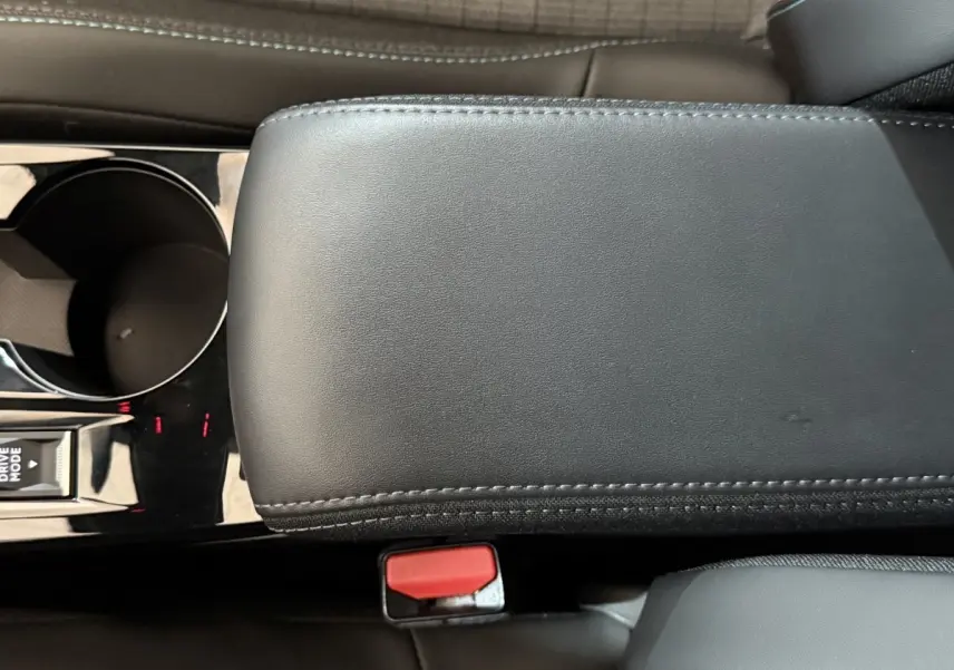 Gros plan intérieur sur l'accoudoir central noir et la console avec porte-gobelet de la Peugeot 2008 gris clair.
