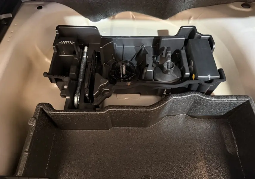 Compartiment de rangement sous le coffre du Peugeot 2008 gris clair, montrant l'organisation des outils et accessoires.