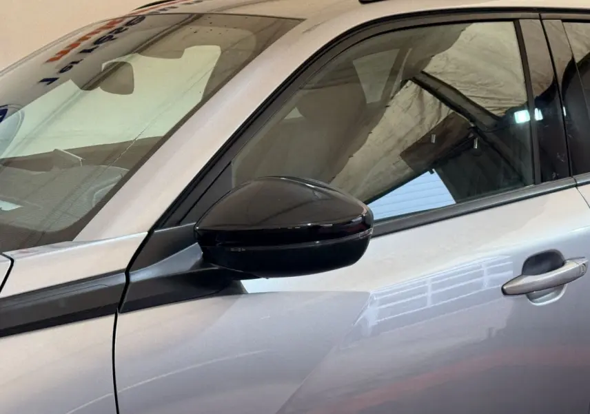 Détail du rétroviseur noir côté conducteur sur la porte gris clair d’un Peugeot 2008 2023.