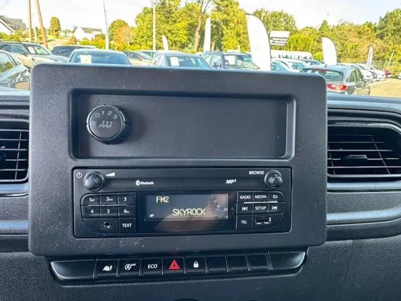 Vue rapprochée du tableau de bord noir du Renault Master Combi 2020, avec radio affichant la station Skyrock.