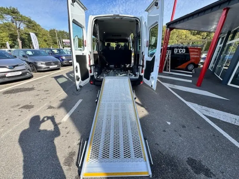 Vue arrière d'un Renault Master Combi blanc avec portes ouvertes et rampe d'accès déployée pour aménagement TPMR.