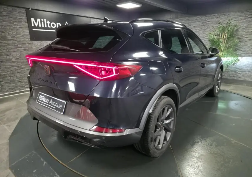 Vue 3/4 arrière droite du CUPRA Formentor bleu avec bandeau lumineux arrière LED et jantes alliage 18 pouces.