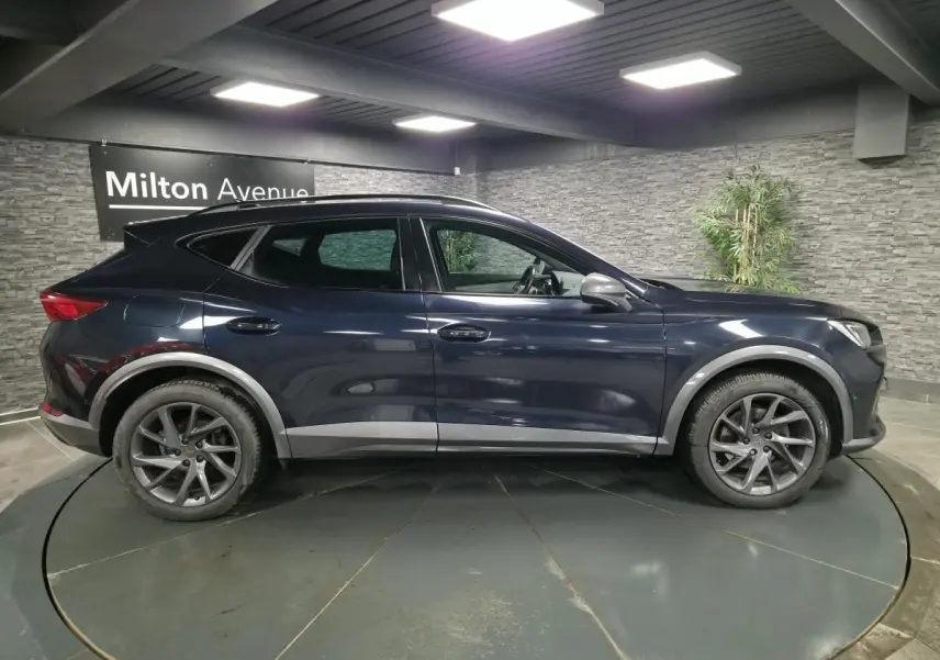 Vue de profil côté gauche d’un CUPRA Formentor bleu avec jantes alliage et détails de carrosserie contrastants gris.