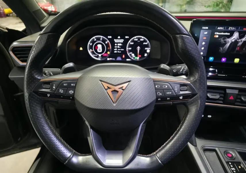Vue rapprochée du volant sport en cuir perforé avec logo CUPRA cuivre et tableau de bord digital du Formentor 2022.