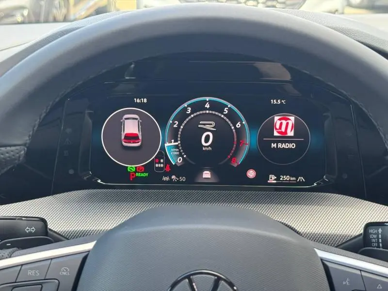 Vue intérieure du tableau de bord numérique de la Volkswagen Golf gris lunaire, affichant le compteur central et les informations de conduite.