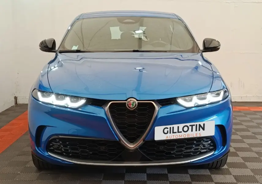 Vue frontale d'une Alfa Romeo Tonale 1.5T Hybrid 160 VGT bleu avec phares LED allumés et calandre caractéristique.