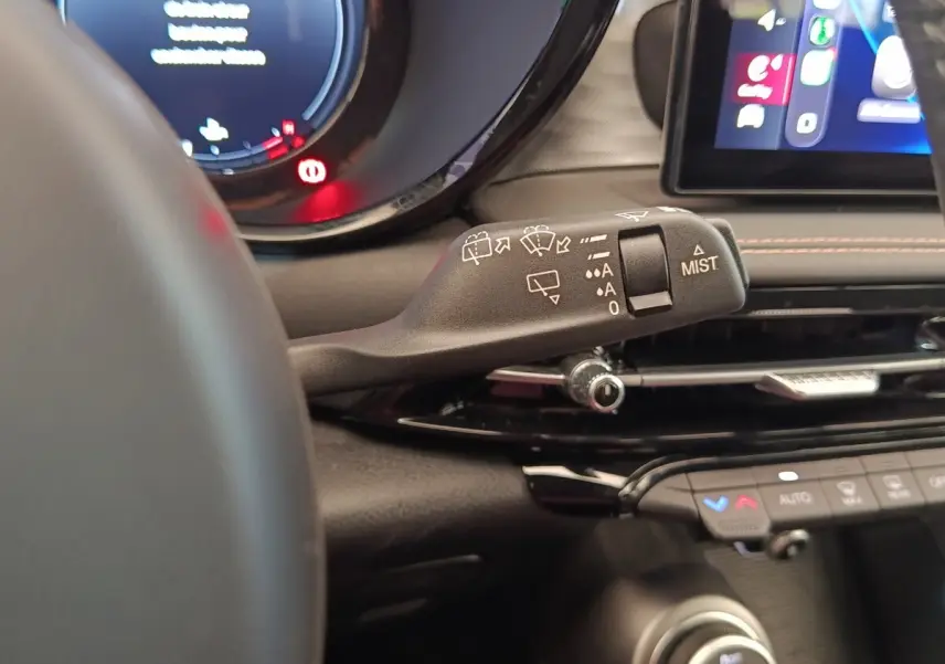 Gros plan sur la manette d’essuie-glace à gauche du volant dans l’habitacle de l’Alfa Romeo Tonale bleu 2023.