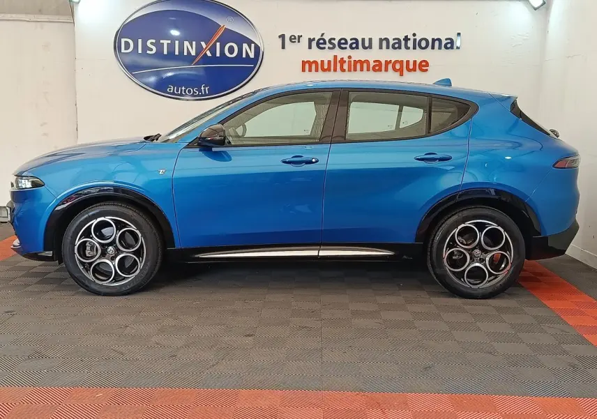 Vue de profil côté gauche d'Alfa Romeo Tonale 1.5T Hybrid 160 VGT bleu avec jantes distinctives en intérieur showroom.
