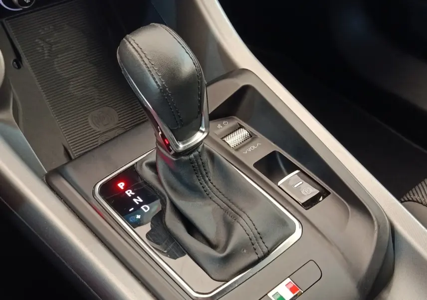 Gros plan sur le levier de vitesses automatique en cuir noir de l'Alfa Romeo Tonale 1.5T Hybrid 160 VGT, intérieur moderne.