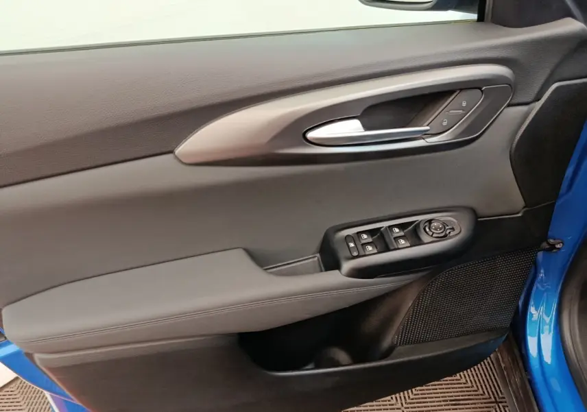 Vue rapprochée de la porte avant gauche bleu d’une Alfa Romeo Tonale 2023 avec commandes électriques et poignée argentée.