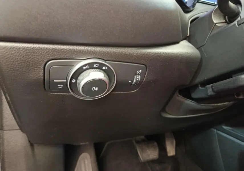 Gros plan sur le bouton de commande des phares noir à gauche du volant dans l’habitacle de l’Alfa Romeo Tonale 2023.