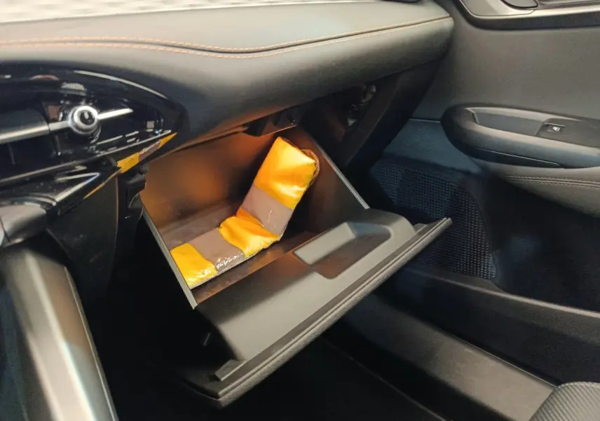 Vue intérieure côté passager de la boîte à gants ouverte de l'Alfa Romeo Tonale 1.5T Hybrid 160 VGT avec gilet de sécurité jaune.