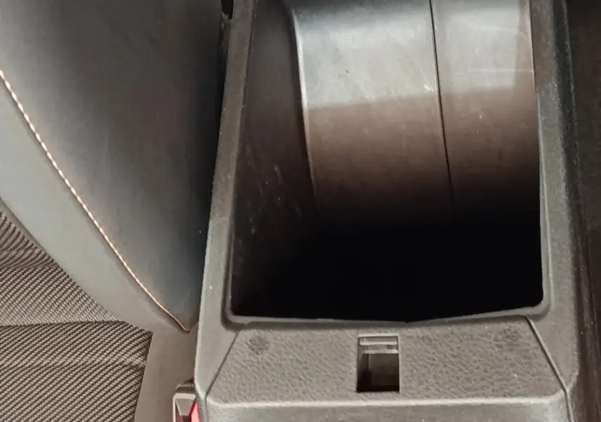 Vue rapprochée de la console centrale ouverte de l'Alfa Romeo Tonale bleu, montrant le rangement intérieur et la sellerie noire.