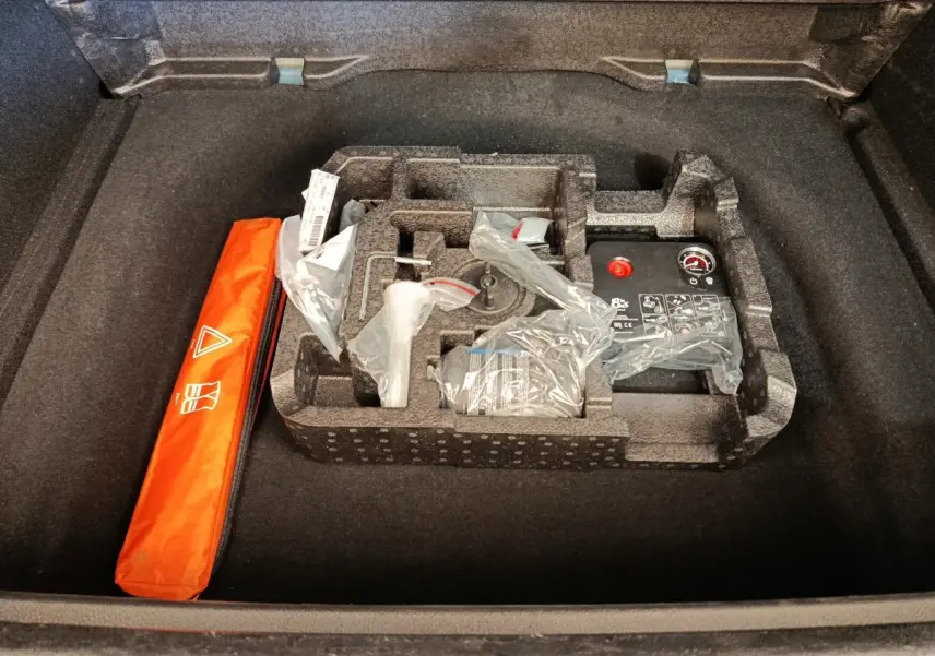 Coffre ouvert d'une Alfa Romeo Tonale bleu, montrant le rangement d'accessoires et la trousse de sécurité orange.