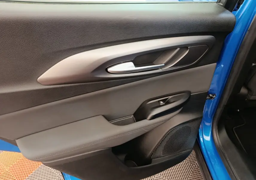 Vue rapprochée de la porte arrière gauche bleu vif de l'Alfa Romeo Tonale 2023 avec poignée argentée et commande de fenêtre.