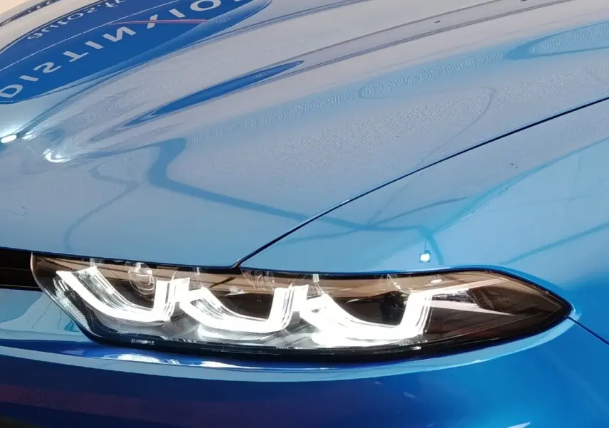 Gros plan sur le phare avant LED d'un Alfa Romeo Tonale bleu, soulignant le design distinctif et moderne.