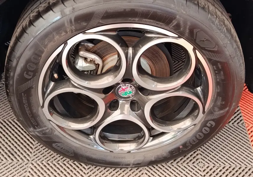Gros plan sur la roue avant droite de l'Alfa Romeo Tonale bleu, avec jante alliage et pneu Goodyear visible.