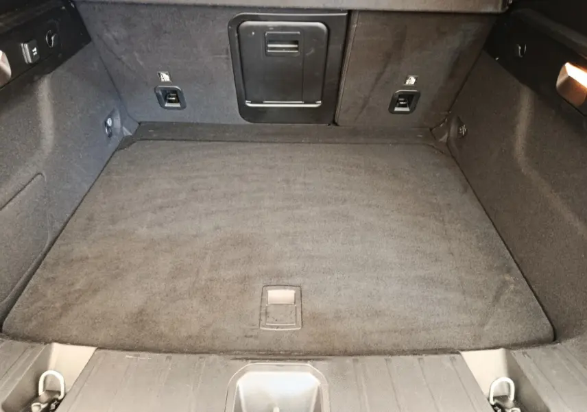 Coffre spacieux de l'Alfa Romeo Tonale 1.5T Hybrid 160 VGT, vue intérieure arrière avec tapis gris foncé.