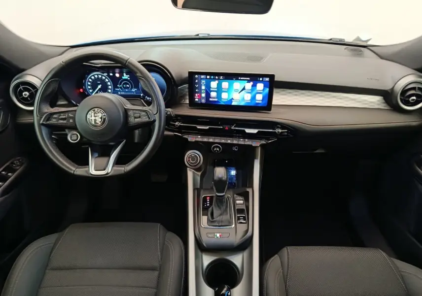 Vue intérieure avant de l'Alfa Romeo Tonale 1.5T Hybrid 2023, tableau de bord noir avec écran tactile central et volant cuir.