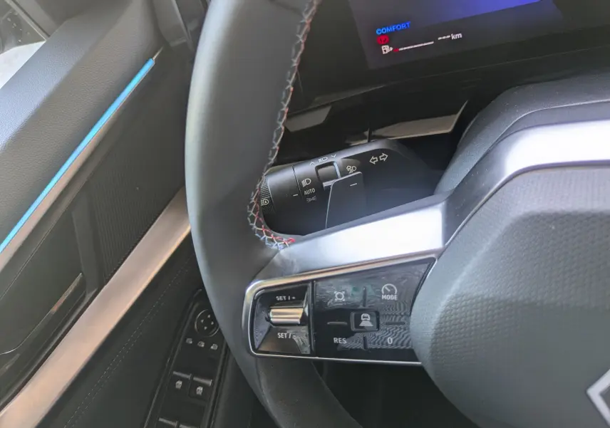 Gros plan sur le volant côté gauche du Renault Espace VI noir étoile, avec commandes multifonctions et coutures tricolores.