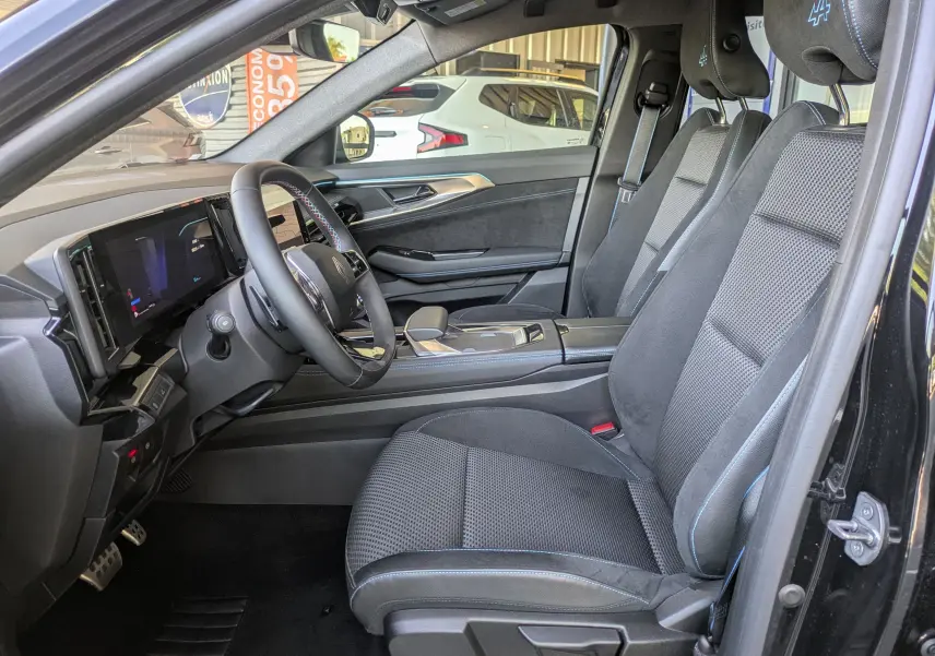 Intérieur côté conducteur du Renault Espace VI noir étoile, sièges tissu/Alcantara avec surpiqûres bleues et logo Alpine sur appui-tête.