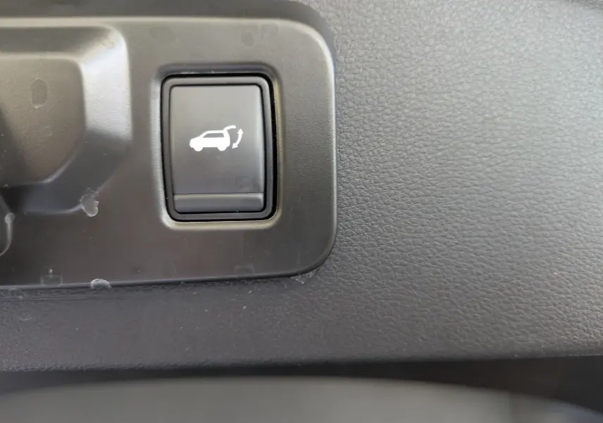 Bouton intérieur noir avec symbole d'ouverture du hayon, sur tableau de bord texturé du Renault Espace VI noir étoile.