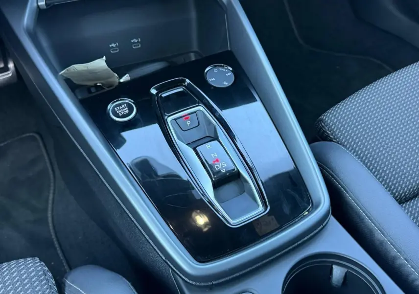 Vue rapprochée de la console centrale noire brillante avec levier de vitesses automatique et bouton Start/Stop dans un Audi A3 Sportback noir Mythic.