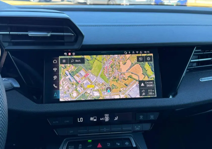 Vue intérieure du tableau de bord de l'Audi A3 Sportback 2025 avec écran GPS couleur et commandes de climatisation.