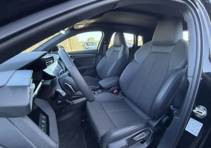 Vue intérieure côté conducteur de l'Audi A3 Sportback 2025 noir Mythic, sièges sport en cuir et tissu avec logo S embossé.
