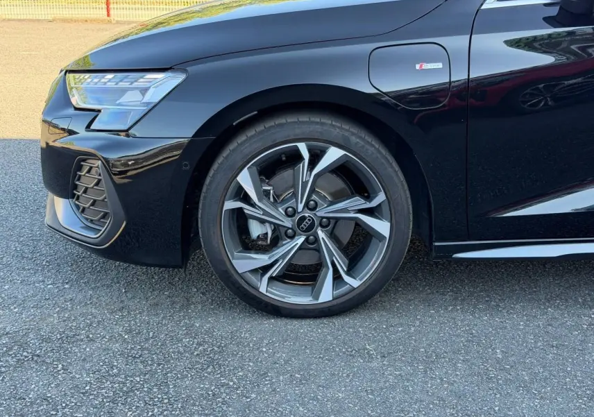 Gros plan sur la roue avant gauche et la partie avant noire métallisée d’une Audi A3 Sportback S line 2025.