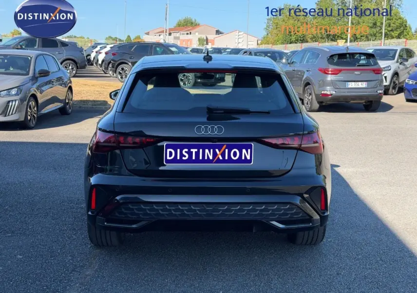 Vue arrière d'une Audi A3 Sportback 2025 noir Mythic métallisé stationnée en extérieur sur parking.