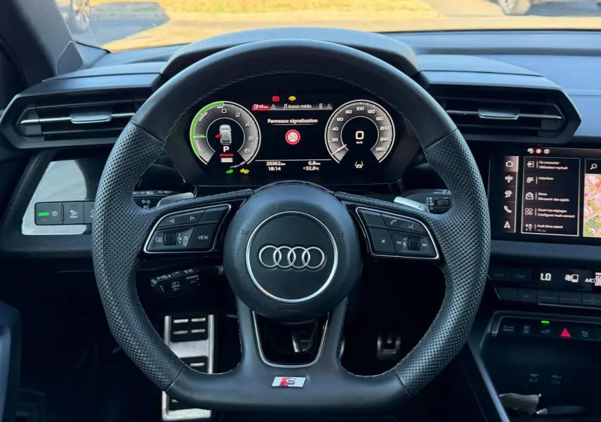 Vue intérieure centrée sur le volant sport Audi S avec tableau de bord numérique et écran tactile à droite.
