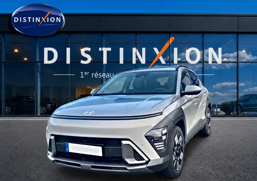Hyundai Kona gris 2025 en 3/4 avant droit, avec feux LED et jantes alliage devant showroom Distinxion.