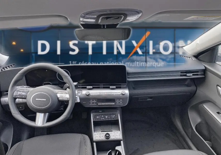 Intérieur avant du Hyundai Kona gris 2025, tableau de bord moderne avec écran large et volant multifonction cuir.