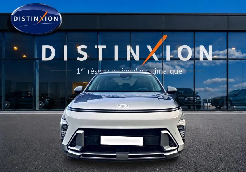 Vue frontale d'un Hyundai Kona gris 2025 avec calandre moderne et feux LED intégrés, devant une vitrine Distinxion.
