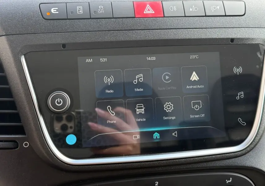 Gros plan sur l'écran tactile central noir du tableau de bord de l'Iveco Daily blanc, avec boutons de commande et interface multimédia.