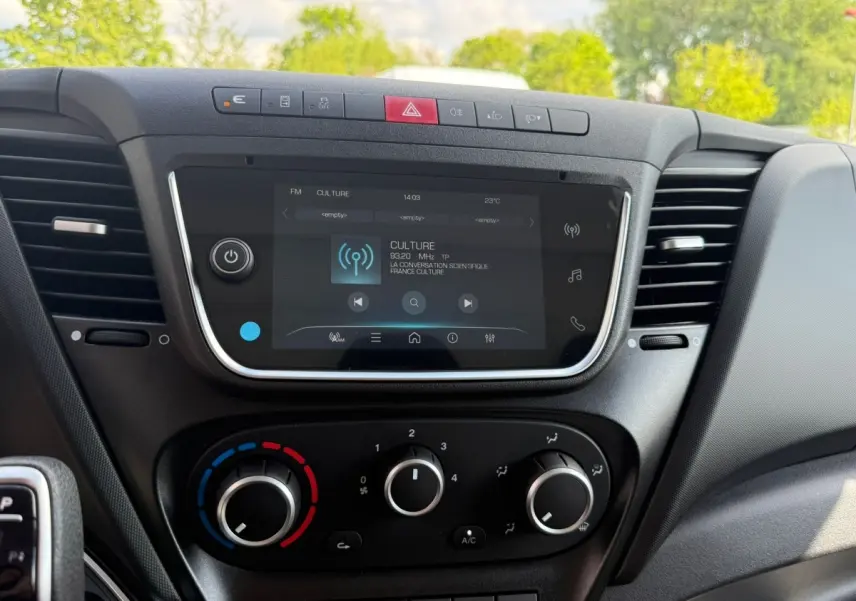 Vue rapprochée de la console centrale noire de l'IVECO Daily 35S18 2026 avec écran tactile et commandes de climatisation.