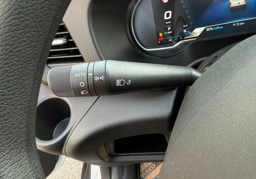 Gros plan sur la manette de commande des phares et clignotants du tableau de bord du Daily blanc IVECO 2026.