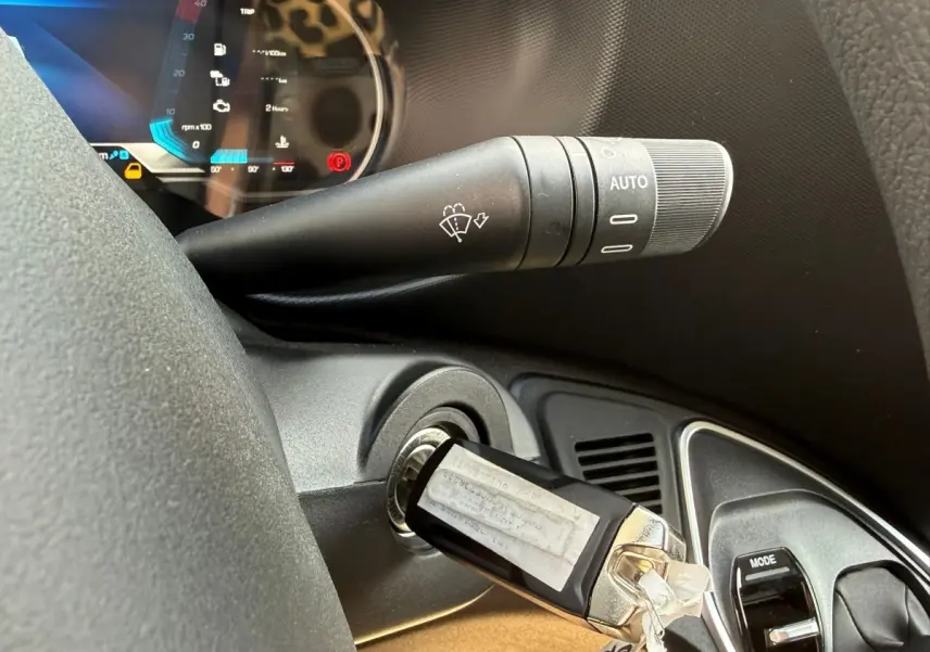 Gros plan sur la clé insérée dans le contacteur du tableau de bord noir de l’Iveco Daily blanc, avec commande d’essuie-glace visible.