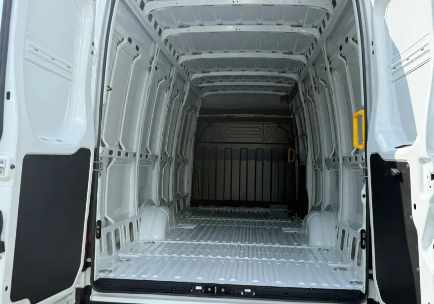 Vue intérieure arrière du fourgon blanc Iveco Daily 35S18 2026, montrant l'espace de chargement vide et les parois métalliques.