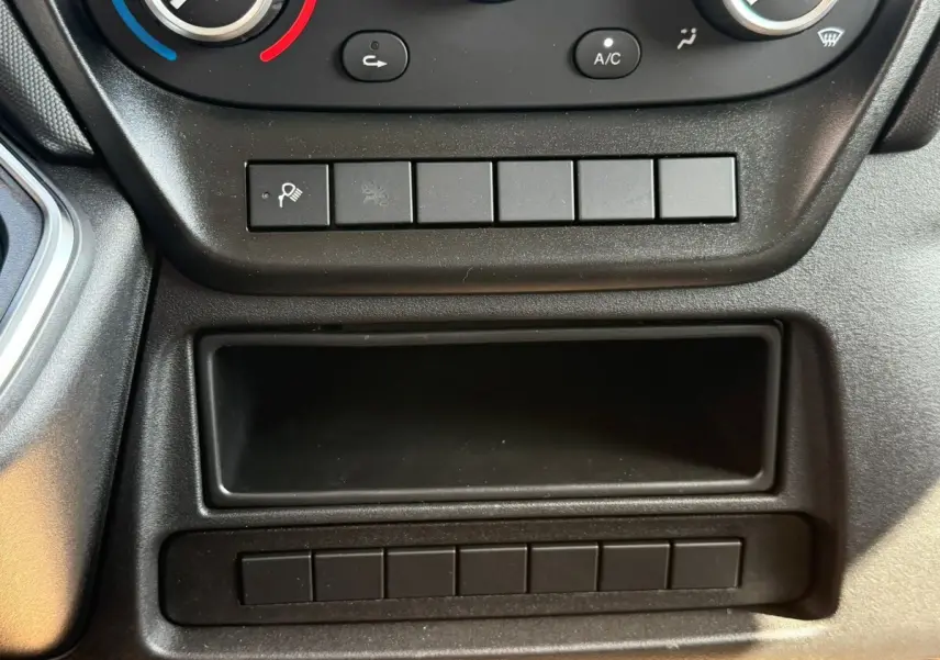 Gros plan sur la console centrale noire de l’IVECO Daily 35S18, montrant les commandes de climatisation et rangements.