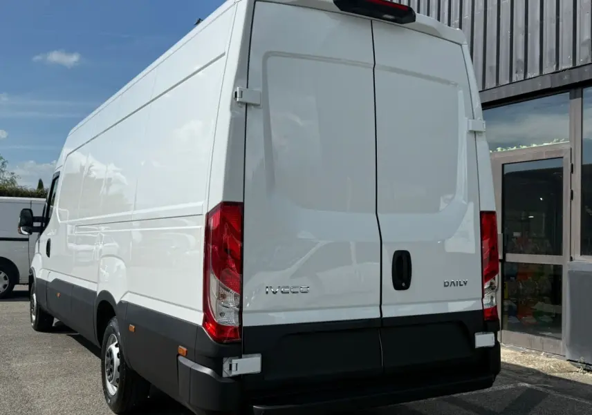 Vue arrière droite d’un utilitaire Iveco Daily blanc avec portes arrière fermées et feux rouges visibles.